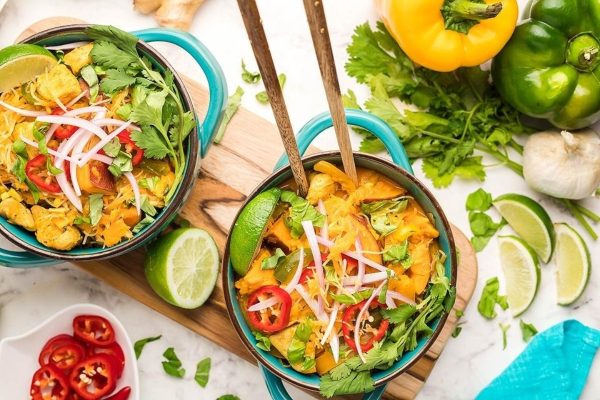 Two bowls of chicken curry on a wooden cutting board.