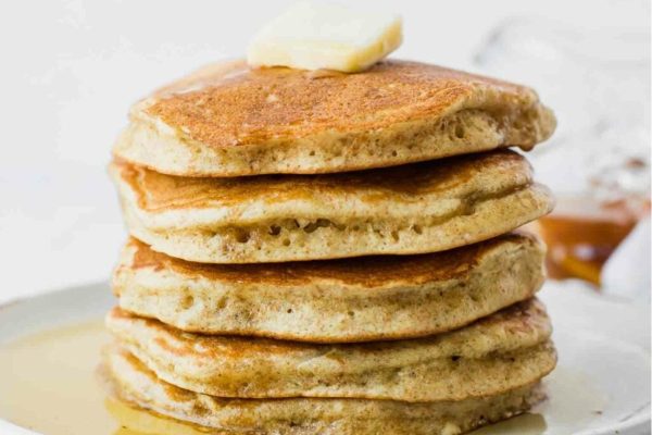 A stack of pancakes with butter and syrup on a plate.