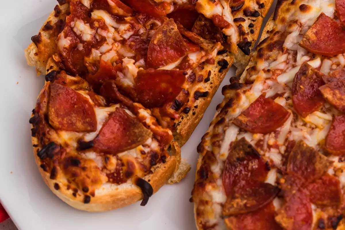 Two slices of bread with pepperoni and cheese on a plate.