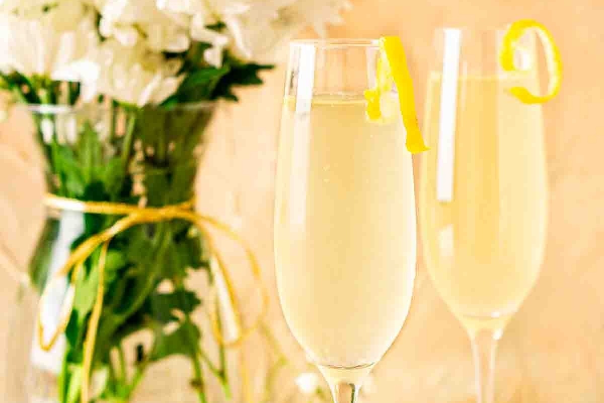 Two glasses of champagne alongside a vase of flowers.