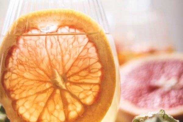 A glass of wine with oranges and grapefruits.