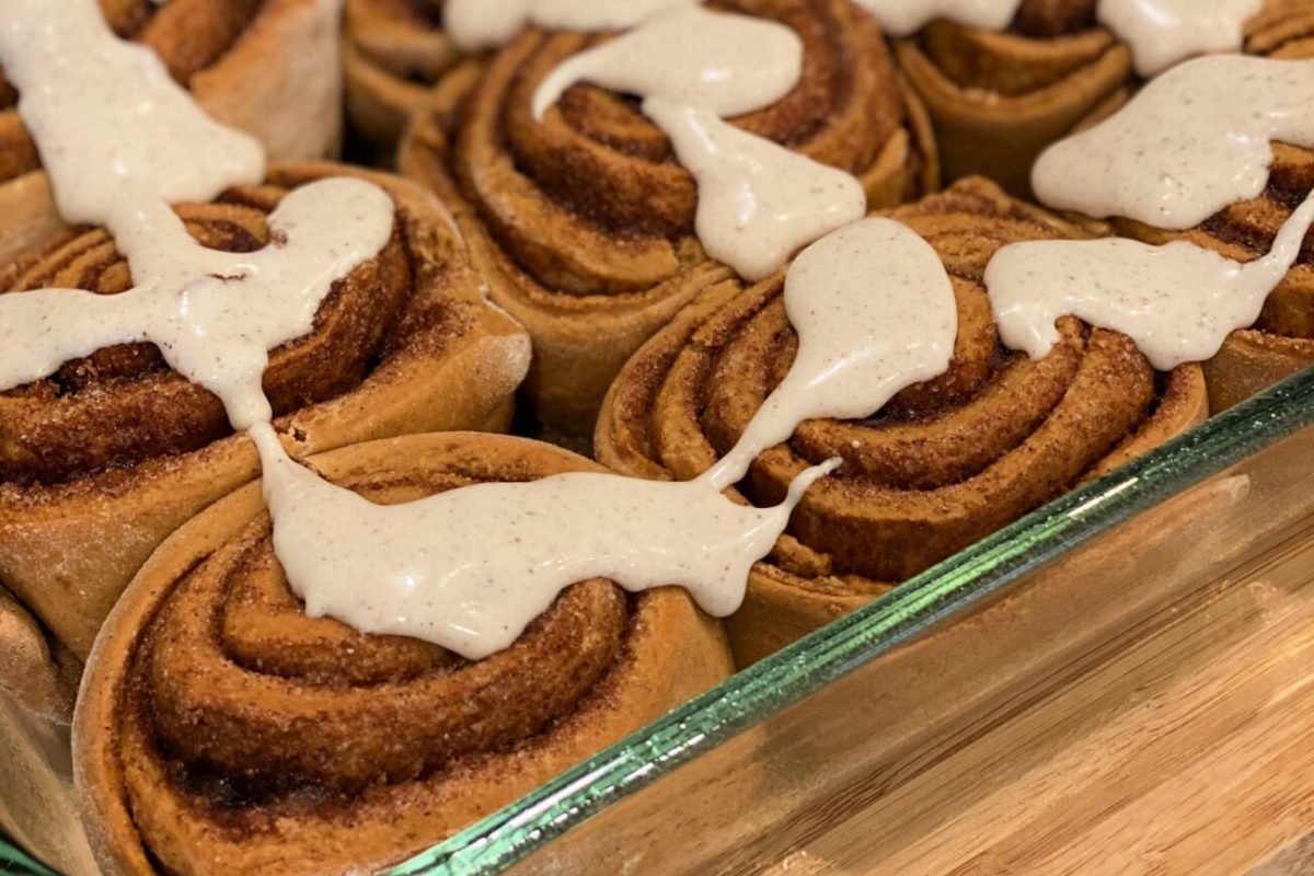 Flavored cinnamon rolls with icing in a glass dish.