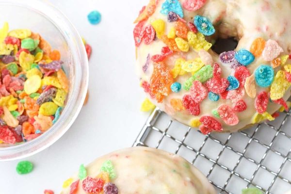 Donuts with sprinkles on a cooling rack.
