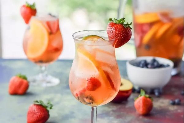 A pitcher of fruity sangria with strawberries and blueberries.