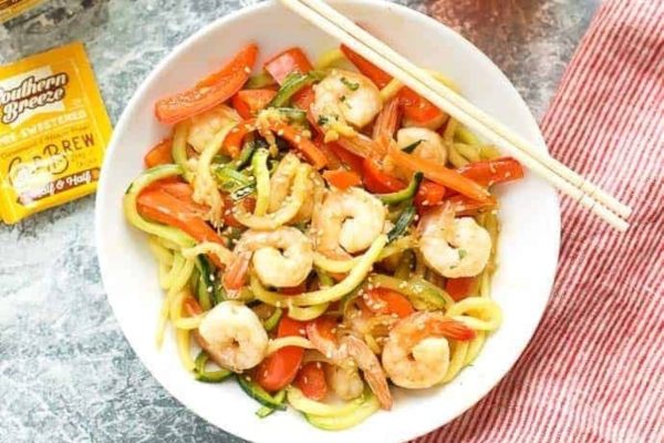 A bowl of shrimp stir fry with vegetables and chopsticks.