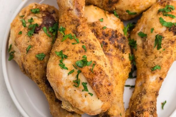 Roasted chicken legs on a white plate.