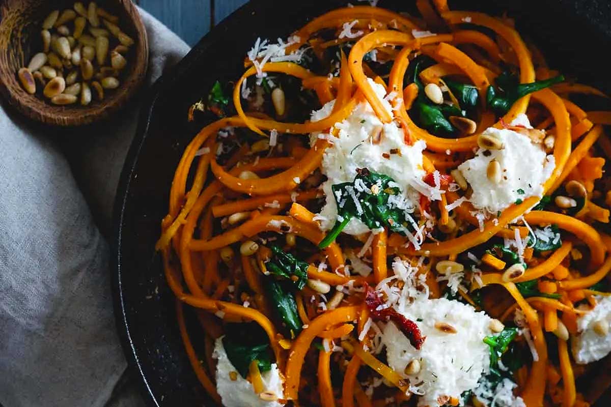 A skillet filled with pasta, spinach and ricotta cheese.