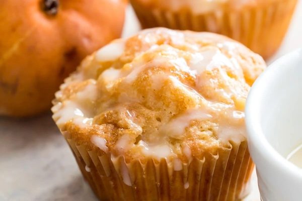 The muffins are sitting on a table next to a cup of coffee.