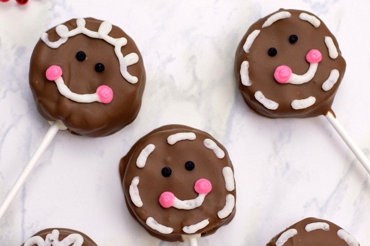 A group of gingerbread pops flavored with chocolate and adorned with smiley faces.
