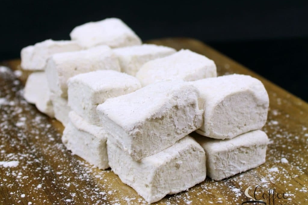 Flavored marshmallows on a wooden cutting board.