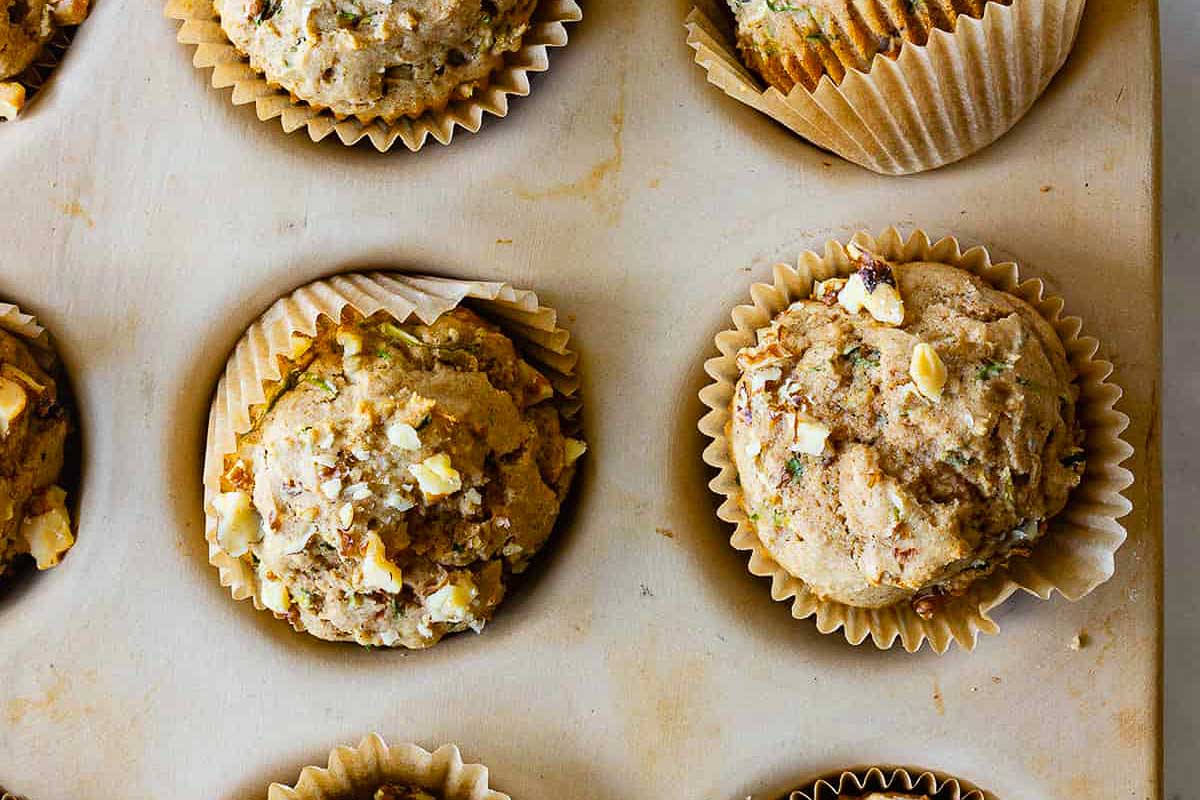 Zucchini muffins in a muffin tin using fresh zucchini.