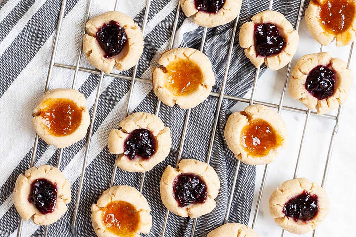 Jam filled thumbprint cookies on a wire rack.