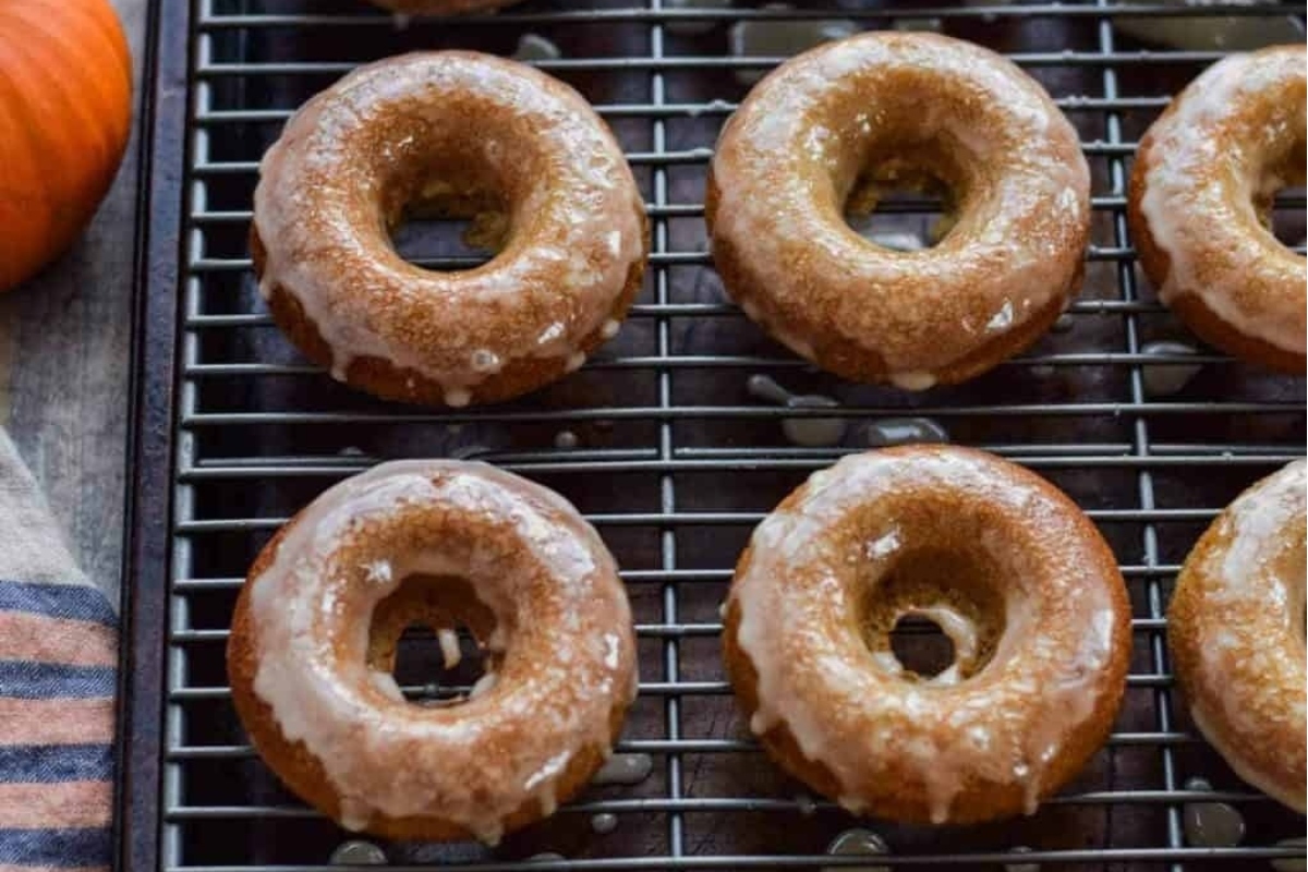 Cinnamon-glazed pumpkin donuts on a cooling rack.