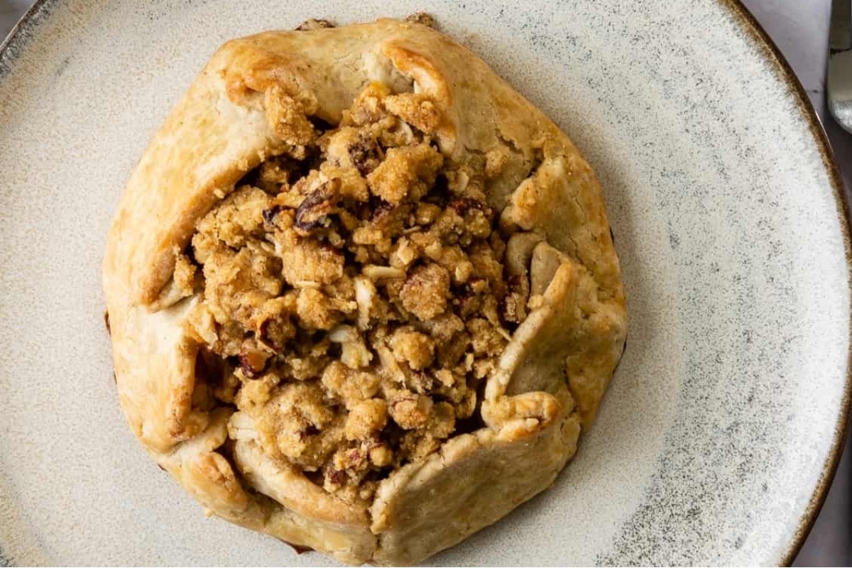 A country style pie with a crumb topping on a plate.