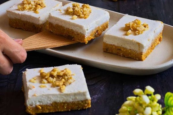 Four traditional squares of cheesecake on a plate with grapes.
