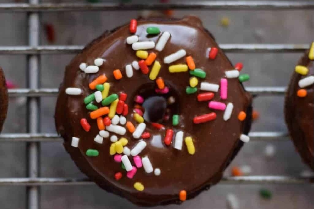 Chocolate donuts with sprinkles on a cooling rack.