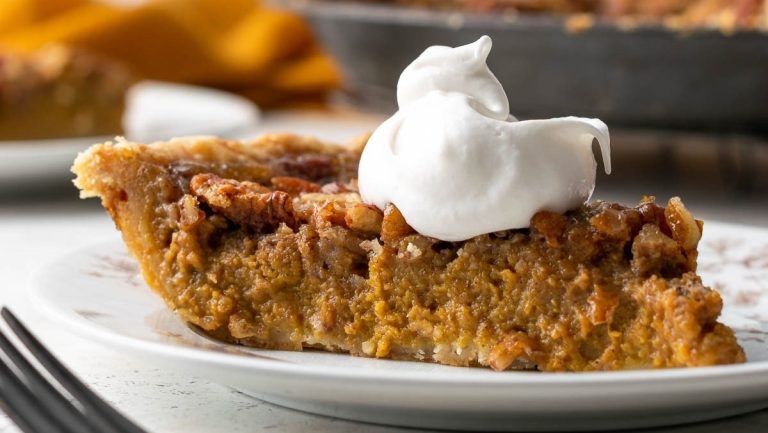 A slice of pumpkin pie with whipped cream on a plate.