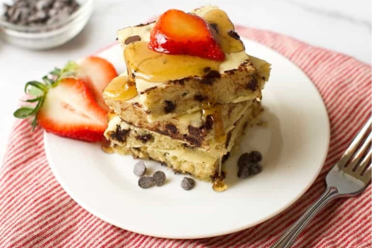 A stack of chocolate chip pancakes with strawberries on a plate, perfect for breakfast or Christmas morning.