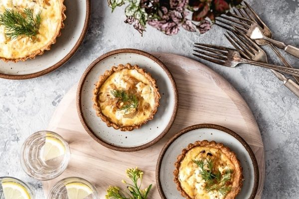 Quiche recipes with dill and lemon on a wooden board.