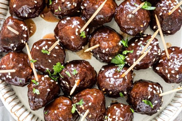 Glazed meatballs on a plate with toothpicks.