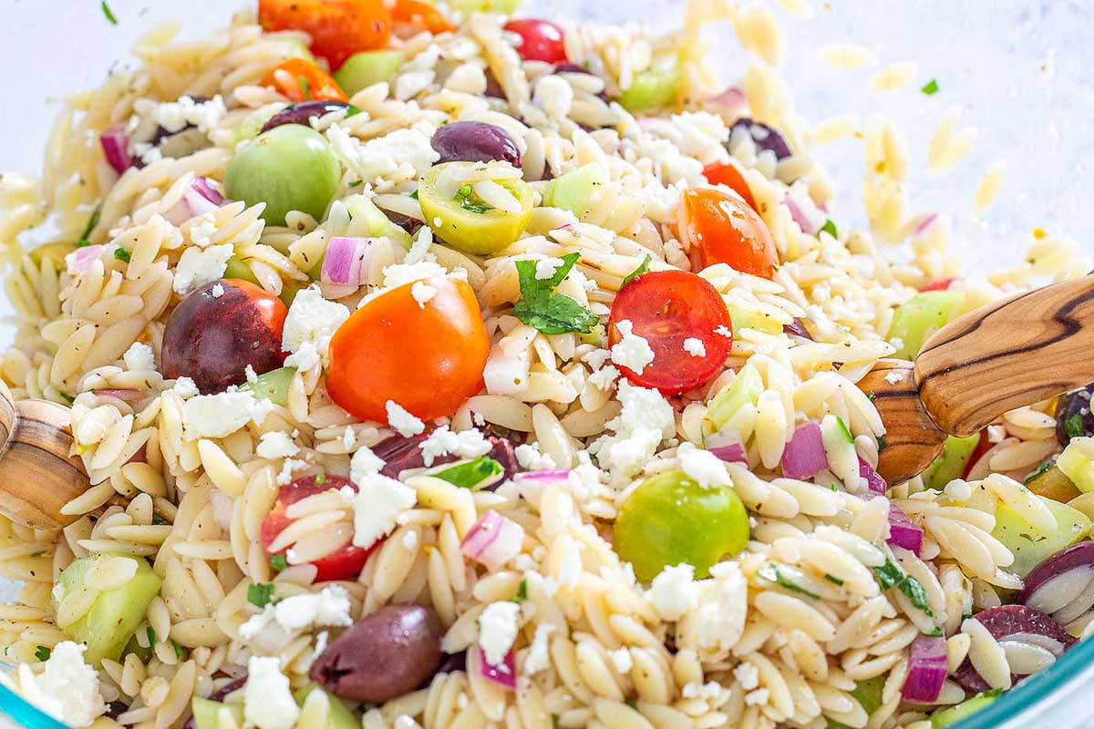 Greek orzo salad in a glass bowl.