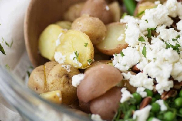 Colorful Christmas salad with potatoes, peas, and feta in a bowl.