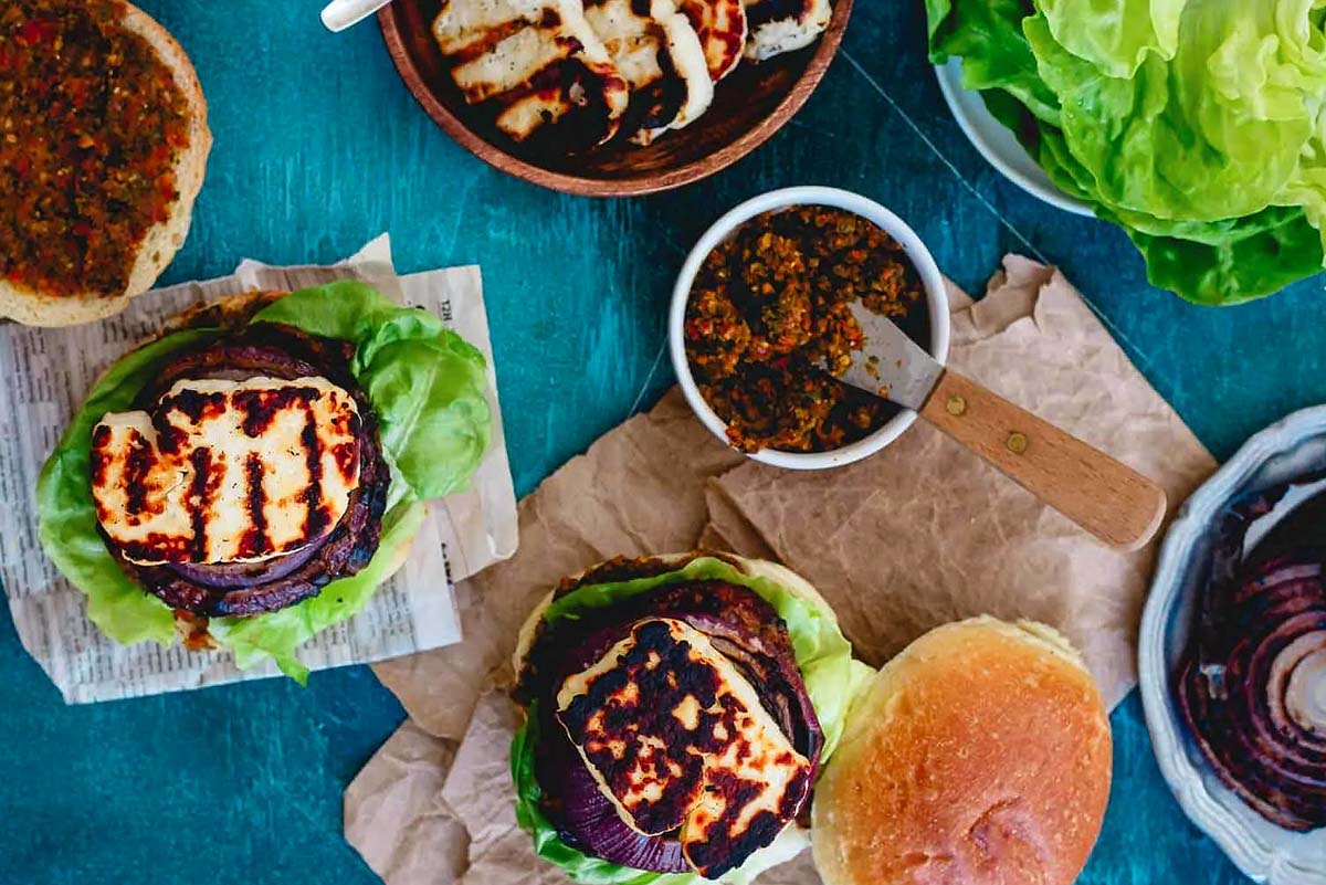 Grilled burgers with lettuce and tomatoes on a wooden table.