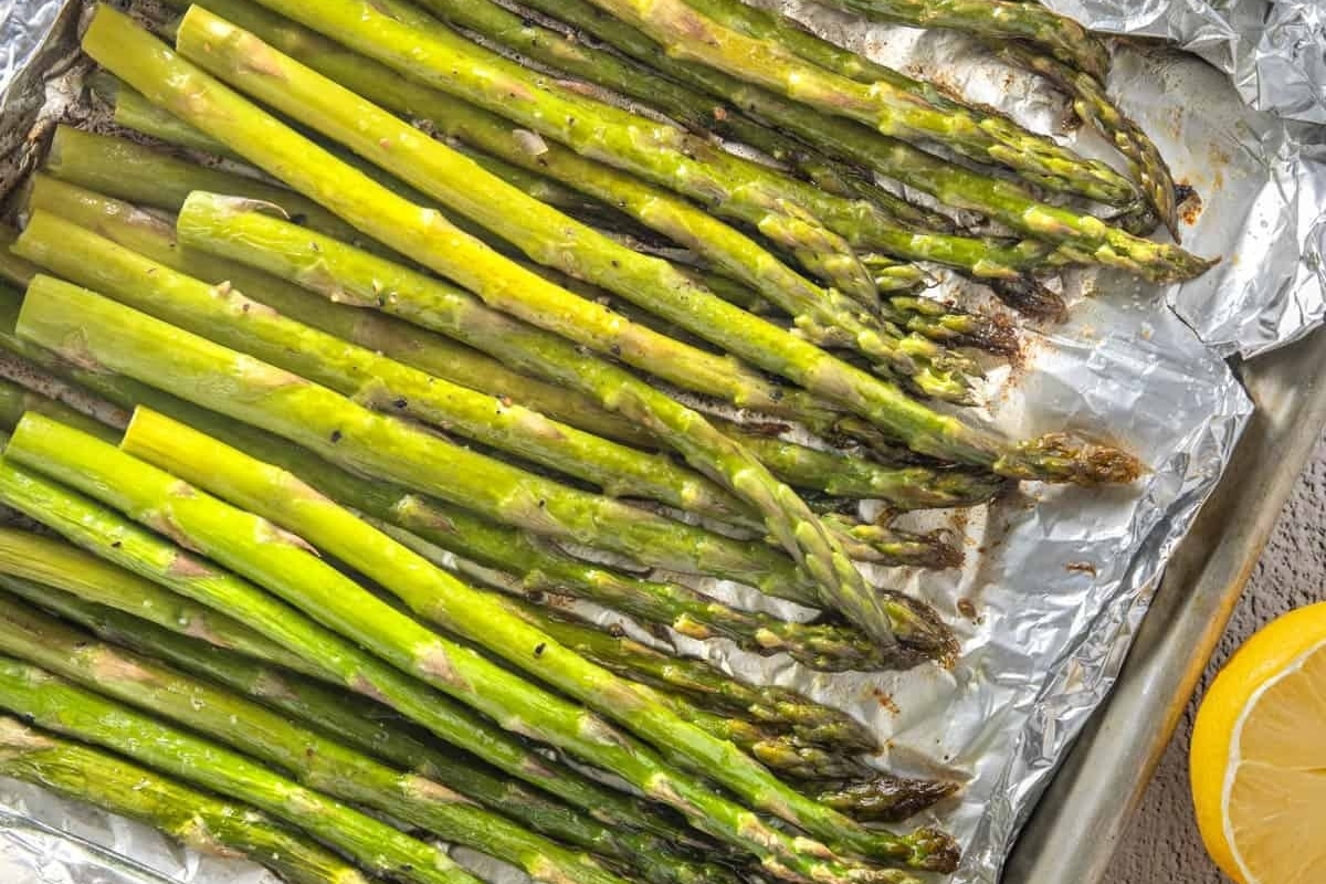 Grilled asparagus on foil with lemon wedges.