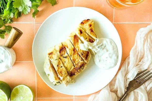 Grilled chicken on a plate with limes and lime juice.