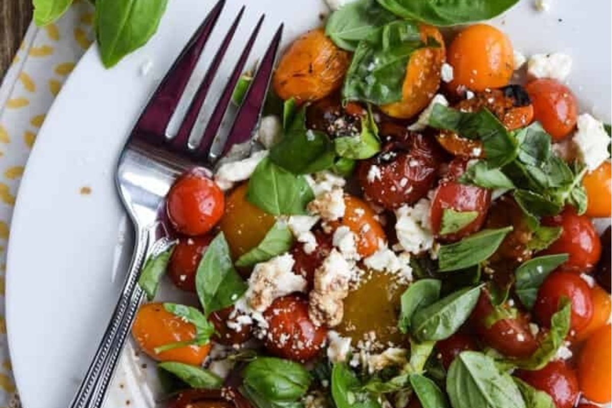 An Italian side dish of tomatoes, basil and feta on a plate.