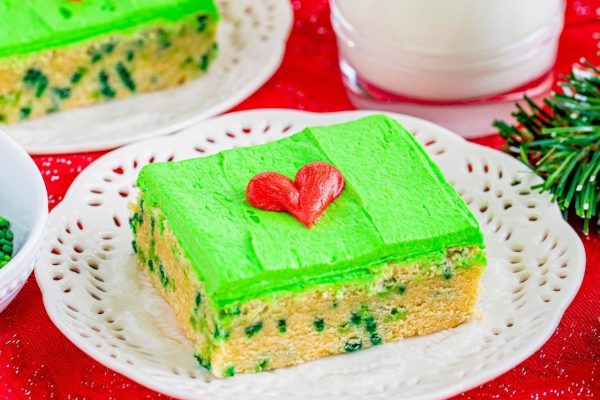 A christmas cake with green frosting and a glass of milk.