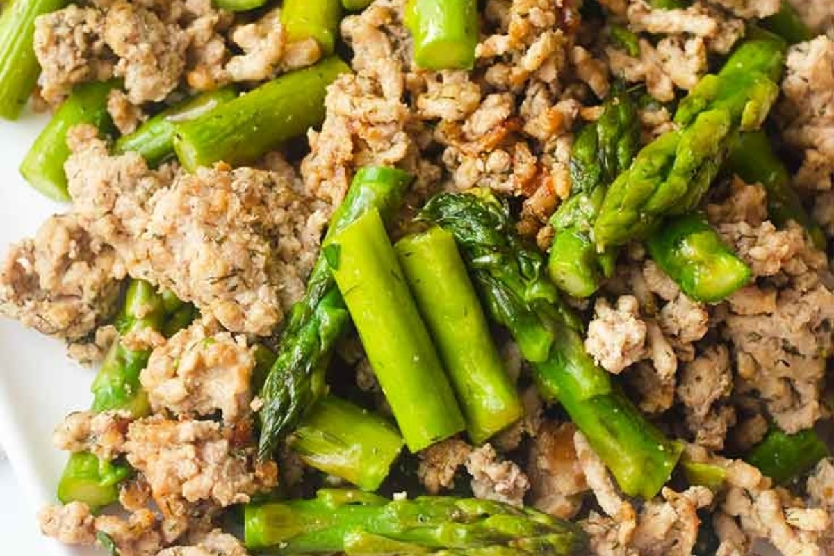A plate of ground turkey and asparagus on a white plate, perfect for healthy recipes.