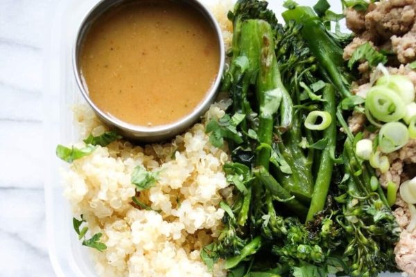 A container with meat, broccoli, rice and sauce.