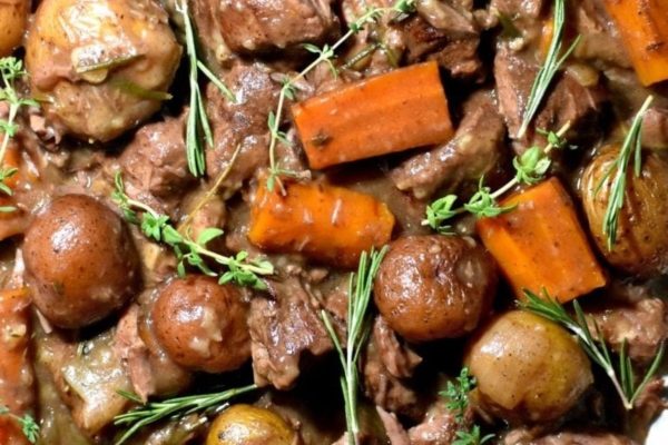A plate of stew with potatoes, carrots and sprigs of thyme.