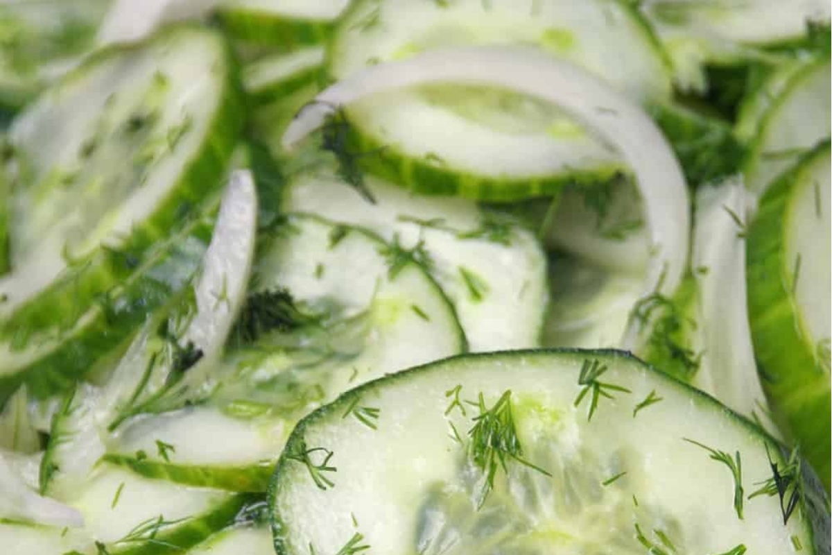 A close up of German cucumber salad, featuring cucumbers and onions in a bowl.