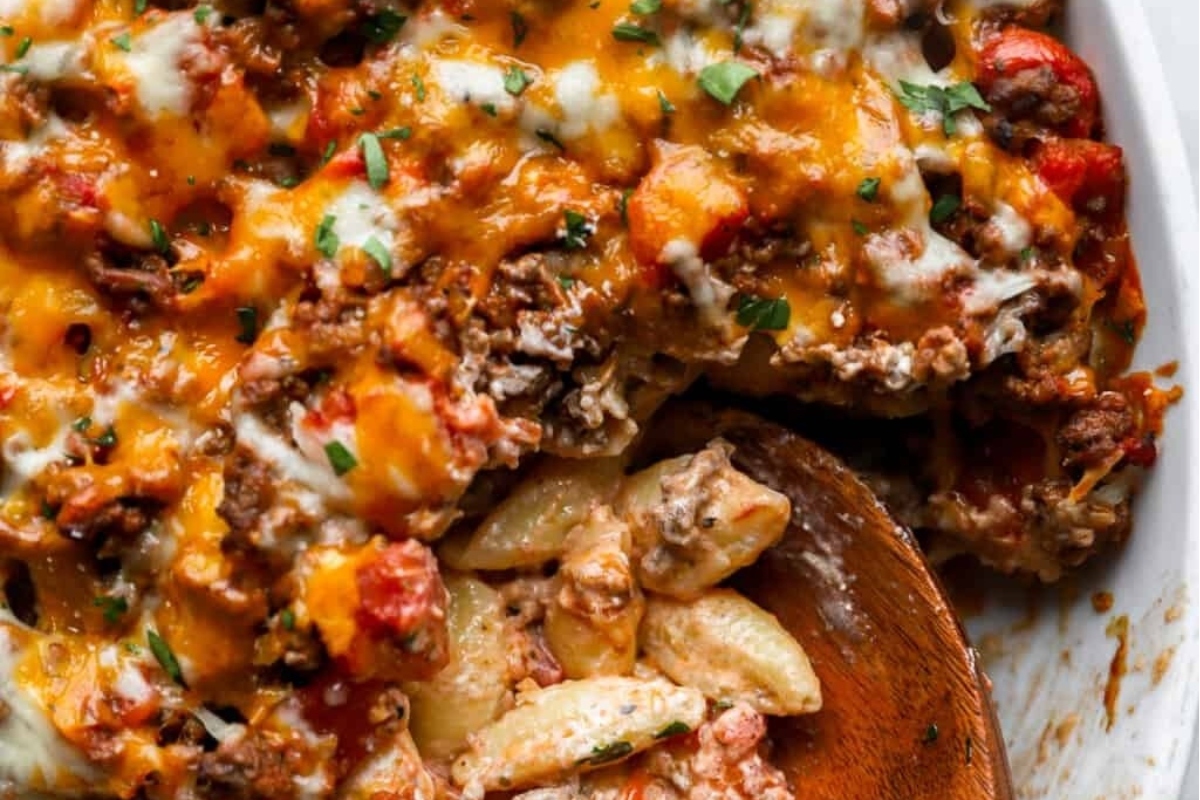 Cheesy pasta casserole with meat and cheese in a white dish.