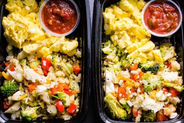 Two plastic containers with meal prep including vegetables and eggs for breakfast.