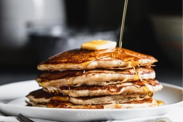 A stack of pancakes with butter being poured over them.