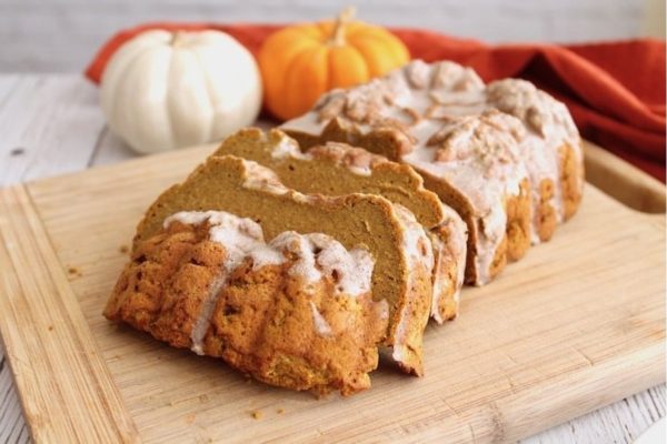 Christmas pumpkin bread with icing on a cutting board.