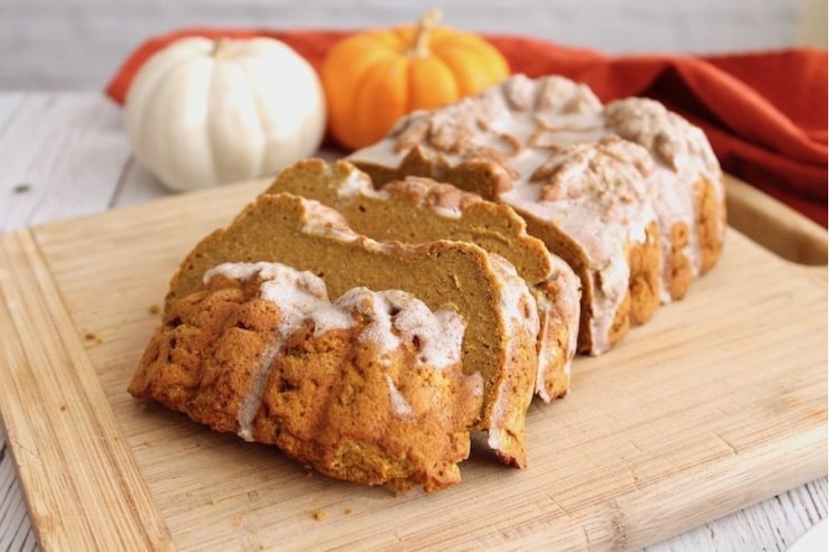 Christmas pumpkin bread with icing on a cutting board.