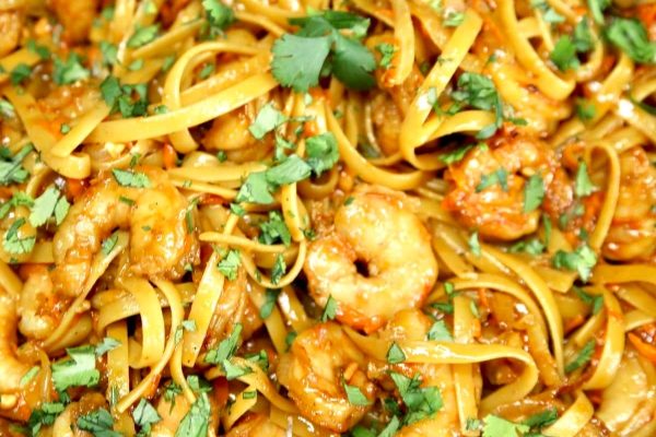 A close up of Asian noodles with shrimp and herbs.