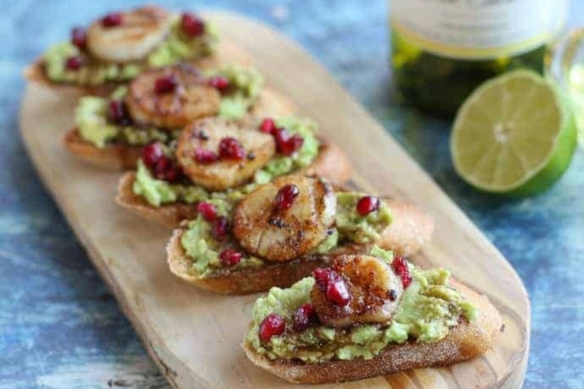 Italian appetizer with toasted bread, guacamole, and pomegranate.