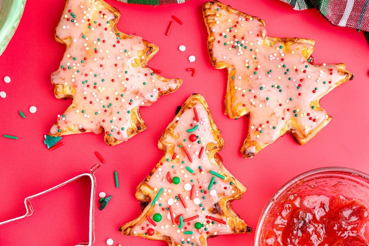 Traditional Christmas cookies with icing and jam on a red background.