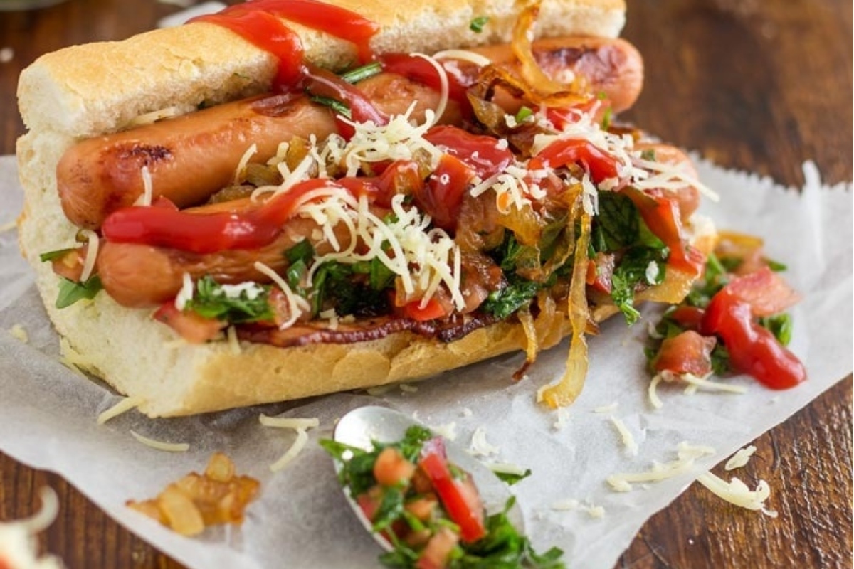 A hot dog, served on a bun with toppings on it.