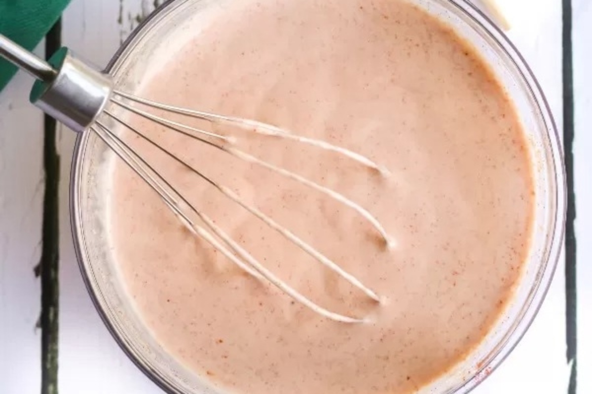 A delicious bowl of sauce being prepared with a whisk.