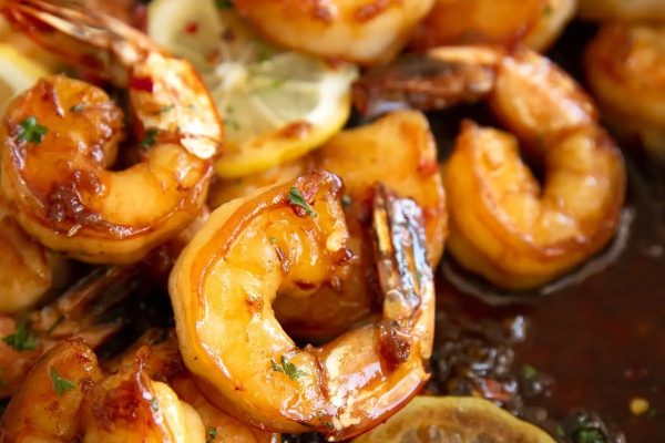 A close up of shrimp and lemon wedges.