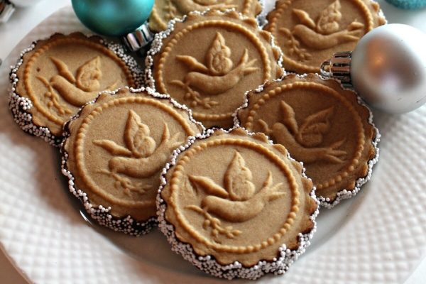 Dove shaped cookies on a plate with ornaments.