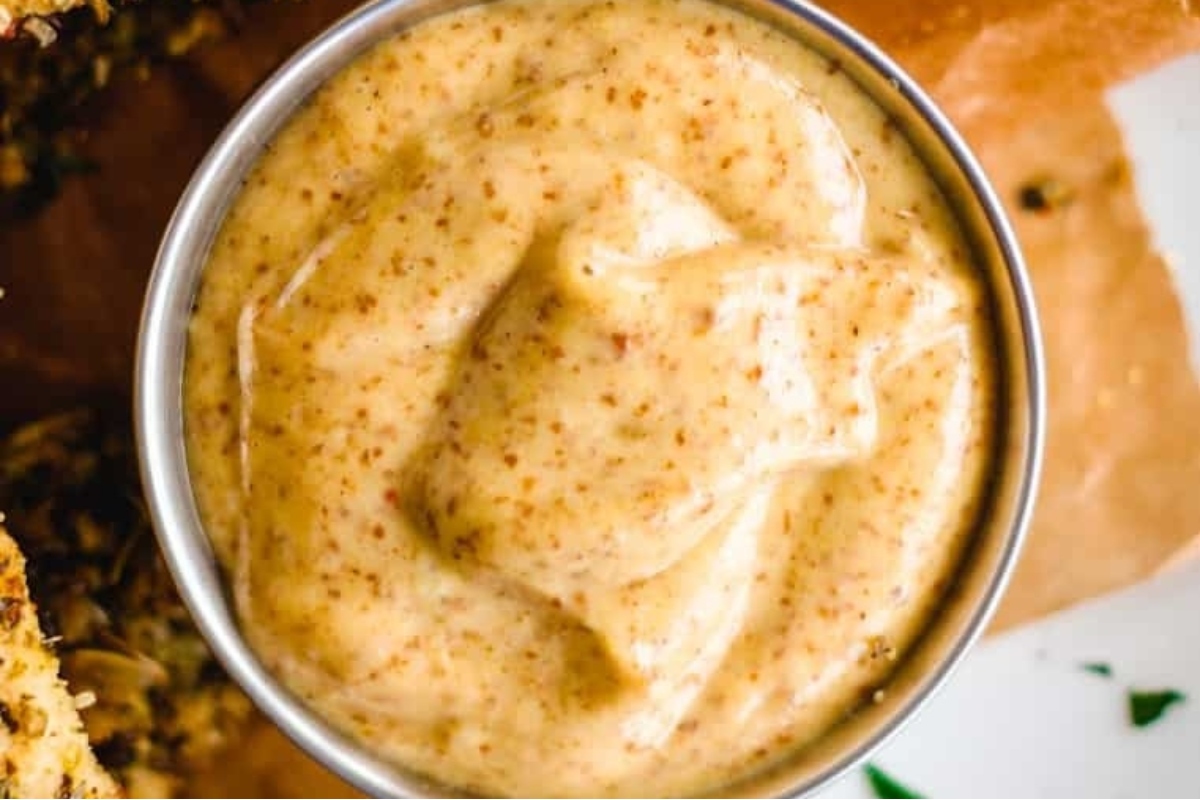 A bowl of hummus sauce with a spoon on top of it.