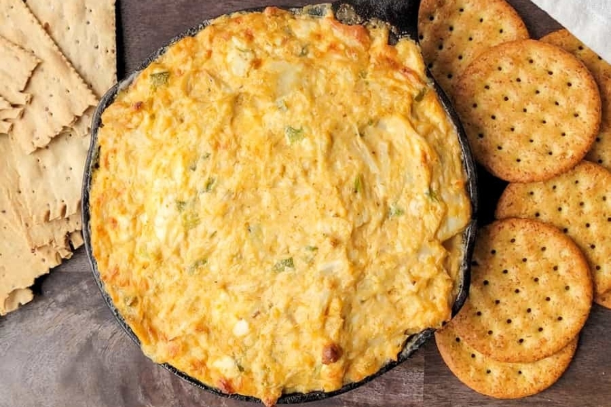 A festive bowl of cheese dip accompanied by an assortment of crackers perfect for Christmas party appetizers.