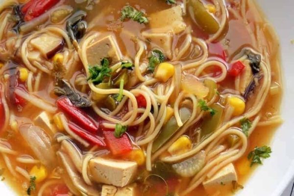 A bowl of asian noodle soup with vegetables and tofu.